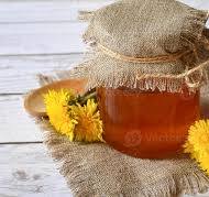 Natural honey in a transparent jar with flowers as ...