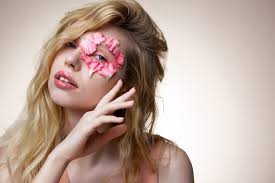 Brillant à lèvres rose. Jeune mannequin séduisante aux yeux bleus avec un  brillant à lèvres rose posant avec des pétales roses sur le visage