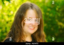 Young fourteen year old teenage girl sits in her bedroom applying makeup in  a mirror in preparation to go out Stock Photo