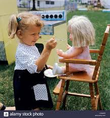 1960s little girl playing feeding doll