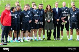 The Duke and Duchess of Cambridge pose with the England team during the  official launch of The Football Association's National Football Centre at  St George's Park in Burton-upon-Trent, England Stock Photo -