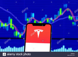 tesla motors logo is seen on an smartphone over stock chart