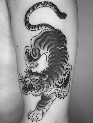 The tiger tattoo in Japanese culture symbolizes strength, courage, and protection. It is believed to ward off evil spirits, bad luck, and disease, embodying power, dominance, and independence. Often associated with resilience