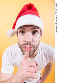 Guy put finger to mouth in red santa hat
