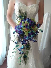 They used feathers for the invitations, place cards, escort cards, menus, and guestbook as well as in the bouquet and boutonniere. Peacock Feather In The Bouquet Www Petalsfromheaven Net Peacock Wedding Theme Peacock Wedding Bouquet Peacock Wedding Decorations