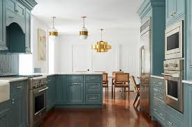 The ceiling features heavy, exposed wooden beams in a dark wood finish and a hanging wrought iron decorative candelabra. Glossy Green Cabinetry With White And Gold Pulls Transitional Kitchen