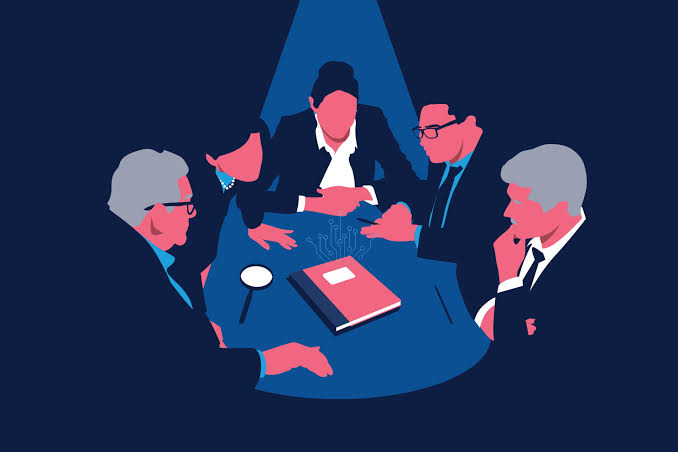 A group of people at a table with a book, and magnifying glass