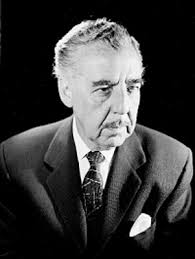 Julian Soler, actor y director cinematografico, de chamarra y camisa, con  brazos cruzados los apoya en el respaldo de una silla, retrato