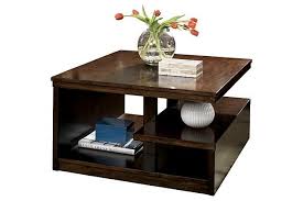 Het frame van geborsteld messing met afgeschuinde randen omgeeft de tafelbladen van rookglas en de onderste planken van spiegelglas. Callum Coffee Table Coffee Table Furniture Ashley Furniture