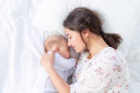 Mãe e bebê recém-nascido dormem juntos mãe coloca bebê para dormir na cama no quarto o conceito de maternidade e sono saudável | Foto Premium