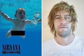 A photo of him as an infant — submerged in water and seemingly chasing a dollar bill dangling from a fish hook. Spencer Elden Celebrities Then And Now Nirvana Nevermind Then And Now