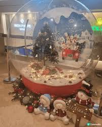 這張圖片展示了一個大型的透明雪球裝置，裡面有聖誕樹和可愛的雪 ...