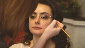Makeup Artist with a Brush Puts Dark Shadows