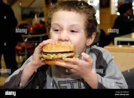 Small boy eating Mcdonald's Big Mac Burger England UK Stock Photo