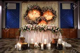 Wedding flowers for bride and groom table. Decor For A Holiday Or Wedding Bride And Groom Table Wreaths Of Fresh Flowers And Burning Light Bulbs On The Background Of A Wooden Wall Stock Photo Picture And Royalty Free Image