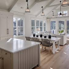 The space features exposed wooden beams with integrated speakers and recessed lighting situated between them. Modern White Cottage Open Concept Living And Dining Room With Vaulted Ceiling Hgtv Coastal Cottage Decorating Modern Farmhouse Kitchens Cottage Interiors