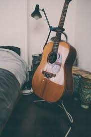 Man in hazmat suit, medical mask and latex gloves holding acoustic guitar on bed. Acoustic Guitar In A Bedroom By Kkgas