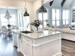 An island counter with overwhelming lighting, this kitchen has both the classic colors of brown and golden. Kitchen Inspiration White Kitchen Kitchen Design Kitchen Pendants Home House Design Living Room Kitchen