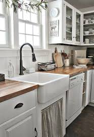 A reclaimed wood backsplash pairs well with a matching wood countertop. Farmhouse Sink White Kitchen Cabinets Wood Flooring Rustic Farmhouse Aesthetics Recabezas Design