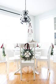 Small Wreath Tied With Ribbon On The Back Of Dining Chairs For Christmas Christmas Dining Room Christmas Dining Table Round Table Decor