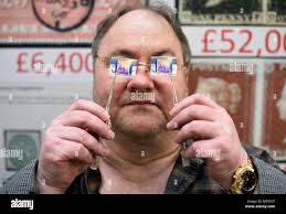 Stamp dealer Mark Bloxham holds up an SG1414a 1988 13p Christmas stamp  (left) worth &pound;8,000, next to a 14p version worth 14p, during the  Stampex philatelic exhibition at the Business Design Centre,