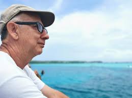 Vista lateral de un hombre con gafas junto al mar contra el cielo