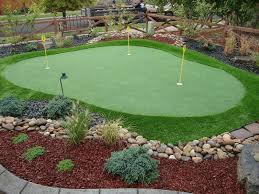 Mini Size Putting Green With Yellow Signs Surrounded By Green Grass Carpet And Some Plant Ornaments Green Backyard Backyard Putting Green Xeriscape Landscaping