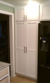 white pantry beside a black fridge