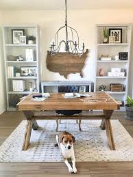 A chic rustic home office with a navy paneled wall, a wooden trestle desk, a basket, a white chair and a shelving unit plus a beaded chandelier. Work In Coziness 40 Farmhouse Home Office Decor Ideas Digsdigs