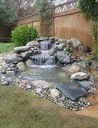 A slim waterfall feeds into the main body, while plant life surrounds and imbues the water itself with flashes of green warmth. 10 Backyard Pond Waterfall Ideas You Ll Absolutely Love Kevin Szabo Jr Plumbing Plumbing Services Local Plumber Tinley Park Il