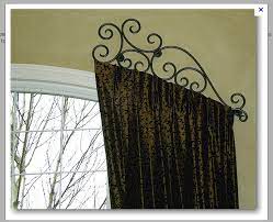 Install a decorative curtain tieback or medallion above the center peak of the arch and one on each side of the window where the arch ends and starts its vertical descent. Drapery Side Panels On Top Curved Window With Custom Made Decorative Rod From Iron Design Center Of Arched Window Treatments Custom Curtain Rods Curved Window