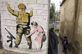 A wall painting by graffiti artist banksy showing israeli border policeman and palestinian in a pillow fight in one of the rooms. Banksy Opens Walled Off Hotel In Bethlehem Middle East Eye