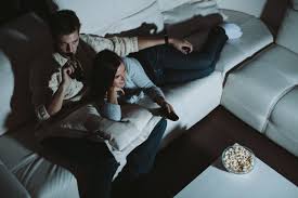 Couple sitting on a sofa reacting to a scary film. Young Couple Watching Tv At Home At Night Romantic Movies Funny Dating Memes Family Movie Night