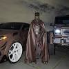 The rapper also posed for the photo in front of a couple of luxury vehicles that matched the color of his batsuit. 1