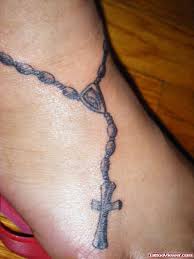 A religious foot tattoo with the lord's cross and a he walks with me… message inscribed on the foot tells a lot about the strong faith the wearer of the tattoo is. Grey Ink Rosary Cross Foot Tattoo