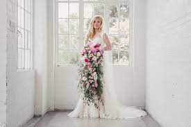 A modern tropical bouquet with a creative shape of white orchids, monstera leaves and a single king protea. A Big Floral Trend Cascading Bouquets Onefabday Com