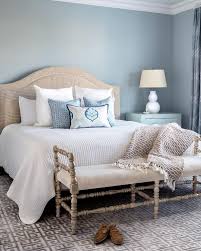 Welcoming Beige And Blue Bedroom Boasts A Gray Wood Bench Placed On A Silver Greek Key Rug In Front Of A Beige Headboard Bedroom Beige Room Blue Bedroom Colors