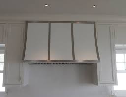 This kitchen offers a white range with matching vent hood in between wooden cabinetry. Custom Vent Hood With White Powder Coat Body