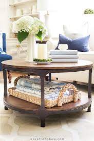 On top you have a glass flower vase holding white blossoms, two fat and tall candles and a bunch tiny burning candles. Simple Round Coffee Table Styling Ideas On Sutton Place
