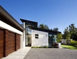 Black And White House With Wood Garage Door White Stucco Black Windows Wood Garage Doors Modern House Exterior Modern Roof Design Garage Door Design