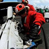 Sgt. Kyle Selman, bottom, and Cpl. Benjamin Cervantes rivet brackets into  the engine space of an F/A-18C Hornet.