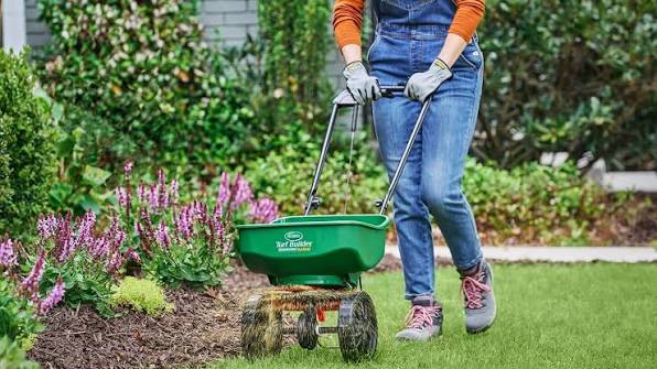 Push broadcast spreader being used along the edge of a lawn