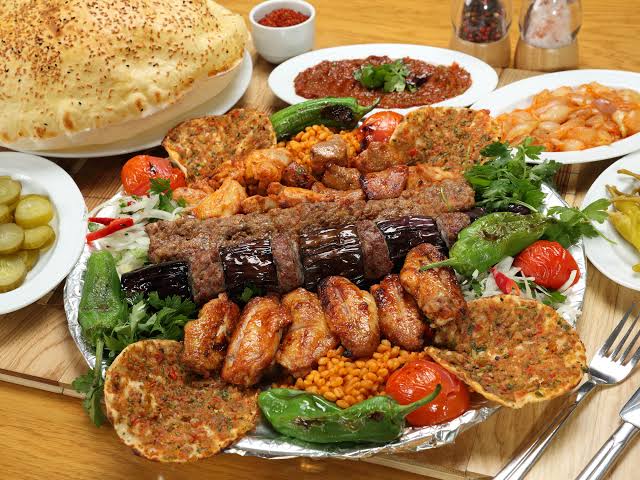 Traditional charcoal-grilled Gaziantep kebab served with roasted peppers and bulgur