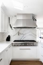 A Gorgeous Black And White Marble Slab Backsplash Holds A Stainless Steel Range Hood Black And White Marble White Marble Countertops Black And White Backsplash