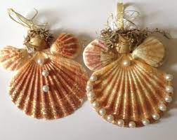 The angel is made of a large white scalloped seashell with rainbow tellin wings, arms are dentalium (a kind of worm shell), her face is delicate pink blossom shells and she is holding a pretty little seashell: Scallop Shell Angel Ornaments Sold In Set Of 2 Free Shipping Diy Xmas Ornaments Seashell Crafts Shell Crafts