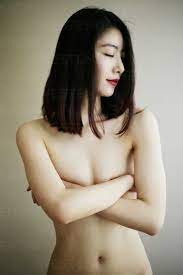Naked Asian woman with arms crossed covering breasts stock photo
