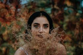 Brunette Woman with Eyes Wide Open Holding flowers in front of her Face ·  Free Stock Photo