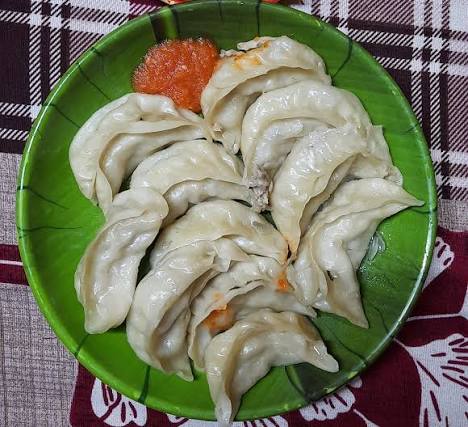 Fresh steamed momos on a plate with red chutney