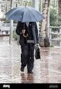 Businessman with umbrella in heavy rain in Spain Stock Photo - Alamy