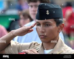 Cross Keys High School ROTC cadet Lucas Ruiz salutes the US flag as he  joins local residents and law enforcement personnel gathered at a weekly  dinnertime food truck roundup in Brookhaven, Ga.,